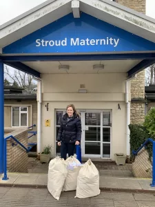 Laura stands in front of Stroud Maternity Hospital with 3 sacks of baby items